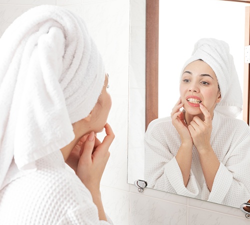 Woman checking her teeth in bathroom mirror