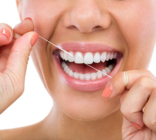 Closeup of woman smiling while flossing her teeth